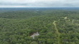 Aerial view of a dense forest with a small pond on a cloudy day.